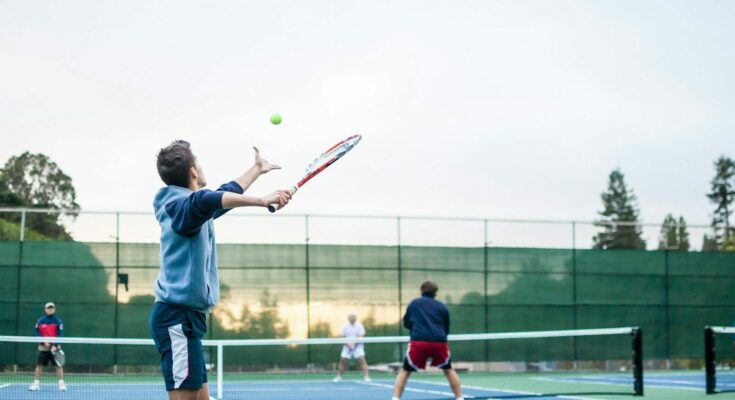four men playing double tennis during daytime