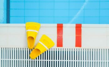 Vibrant yellow swim fins placed by the edge of a clear swimming pool, ideal for aquatic sports.