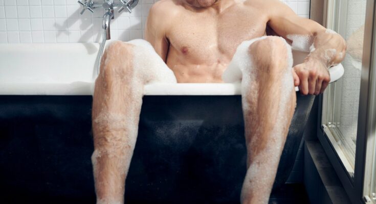 topless man sitting on bathtub